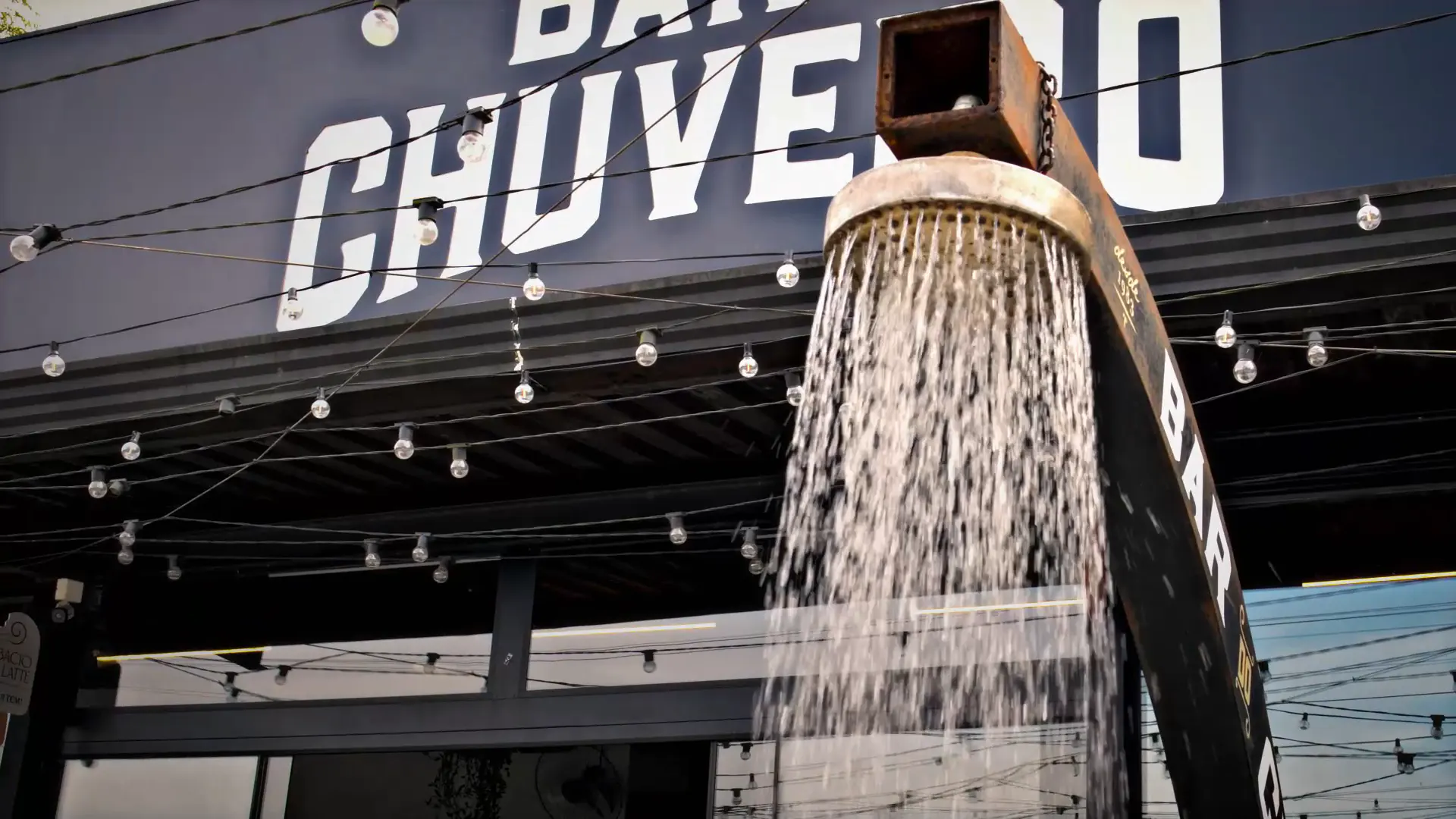 O chuveiro do Bar do Chuveiro de perto, com a água caindo, debaixo do letreiro